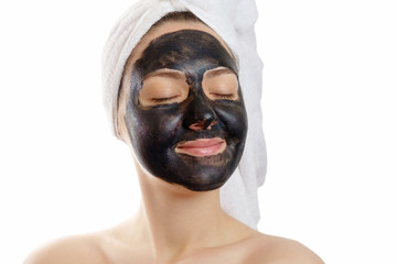  close-up portrait beautiful woman with facial black mask on white background, girl with a white towel on her head, satisfied and happy closed eyes