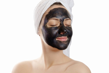  close-up portrait beautiful woman with facial black mask on white background, girl with a white towel on her head, satisfied and happy closed eyes