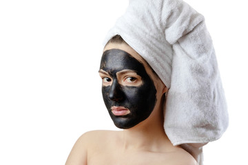  close-up portrait beautiful woman with facial black mask on white background, girl with a white towel on her head, serious look