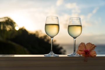 Romantic moments in summer at sunset with two glasses of white wine - Relaxing romantic holiday concept with beautiful view of tropical beach and coast