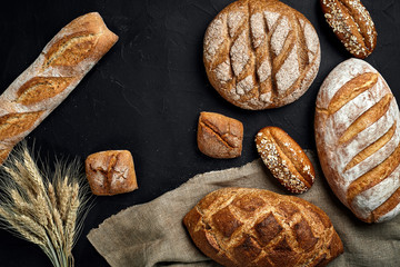 Bakery - gold rustic crusty loaves of bread and buns on black chalkboard background.
