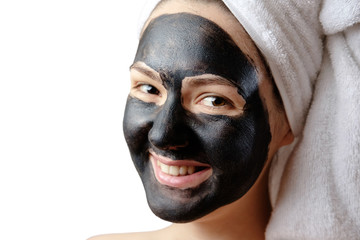  close-up portrait beautiful woman with facial black mask on white background, girl with a white towel on her head, satisfied and happy  smile