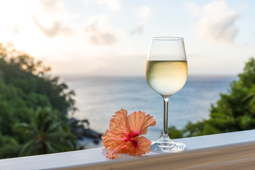 Romantic moments in summer at sunset with two glasses of white wine - Relaxing romantic holiday concept with beautiful view of tropical beach and coast
