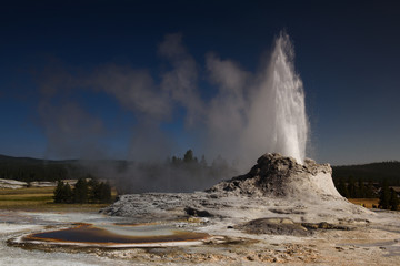 Erupting castle geyser and tortoise shell pool in Yellowstone national park
