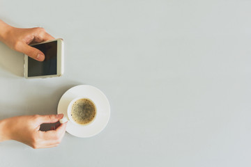 Hands woman using smart phone on grey wooden table. Coffee time. Morning ritual. Top view. Copy space. Toned