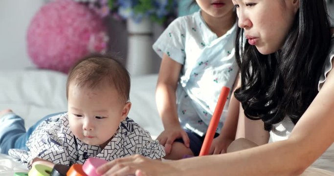 Young beautiful asian woman teaching and play with child at home with smile face