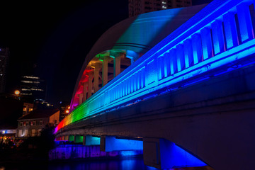 Rainbow colors light the Elgin Bridge at night in downtown Singapore