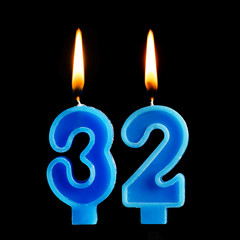 Burning birthday candles in the form of 32 thirty two for cake isolated on black background.