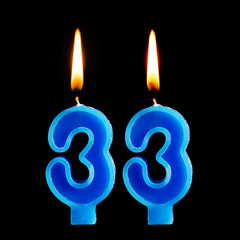 Burning birthday candles in the form of 33 thirty three for cake isolated on black background.