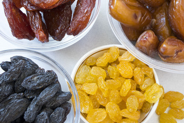 dried fruits in plates-grapes, prunes, dates on gray background