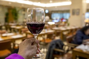 Female hand with a glass of wine on the background of restaurant