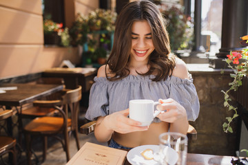 Pretty young woman smiling keeping cup of tea in restaurant