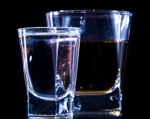 A glass of vodka and a glass of brandy, whiskey or bourbon on a white or colored background