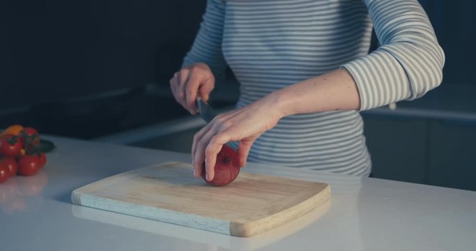 Young woman cutting onions in her kitchen