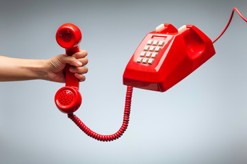 Hand holding telephone, classic red telephone receiver