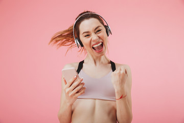 Fototapeta premium Happy sportswoman in headphones running with smartphone and rejoices