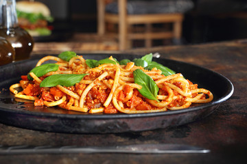 Wege. Makaron spaghetti z pomidorami podane na czarnym talerzu