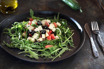 Zielona sałatka na rukoli, z arbuza, tofu, czarnych oliwek podana na czarnymi  talerzu