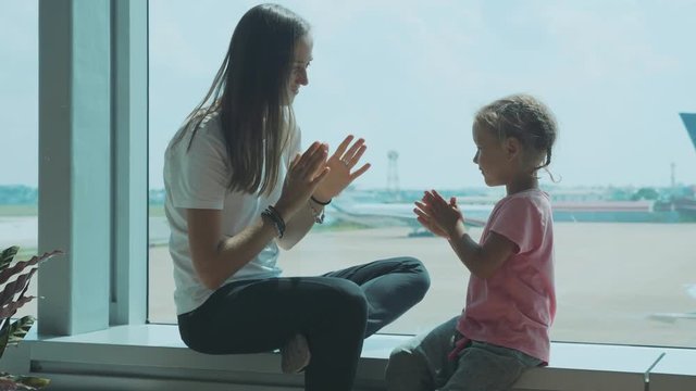 Yound mother and little cute daughter having fun at airport in slow motion.