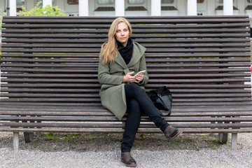 Young beautiful friendly woman sitting on a park bench