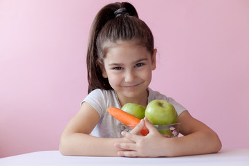 Fototapeta premium A cute little girl eating fresh vegetables. A portrait on ? pastel background. Healthy teeth.