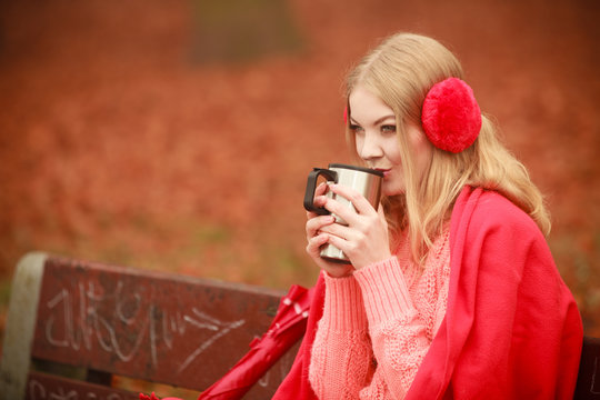 Girl in autumn park enjoying hot drink