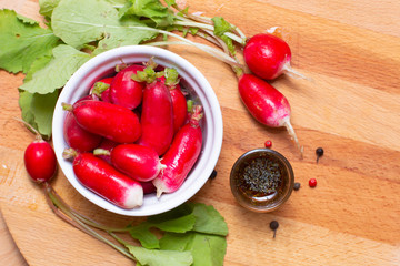 Food preparing oraganic radish in withe cup with dressing salad and spices on wood board