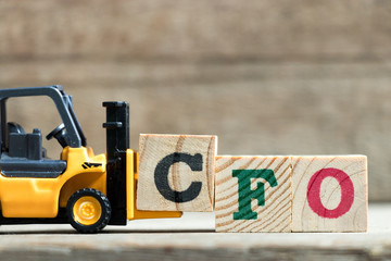 Toy yellow forklift hold letter block C to complete word CFO (Abbreviation of Chief Financial...