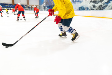 Hockey player in a yellow tank top and red gloves for people drives the puck. Training game, the object is blurred in dynamics.
