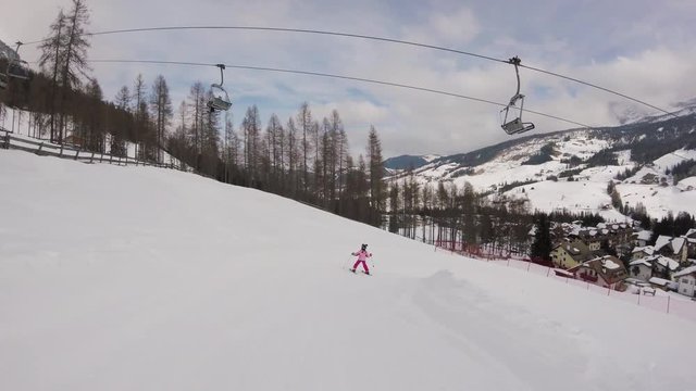 February 2018, La Villa, Italy - Little girl skiing with a beautiful view on a village in mountains
