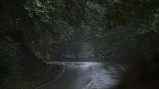 Shot of the Professional Motocross Driver Riding on His FMX Motorcycle on the rear wheel in the rain 4k