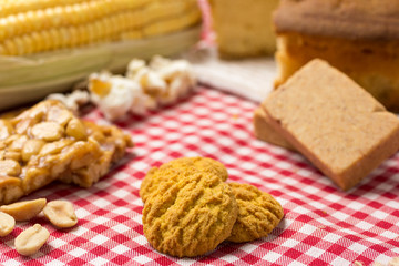 Delicious yellow cookie of corn. Sweet food of Festa Junina, a typical brazilian party. Red plaid fabric on table.