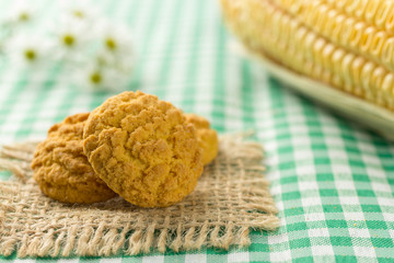 Delicious yellow cookie of corn. Sweet food of Festa Junina, a typical brazilian party.  Snack on wicker basket and green background. Corn cob.