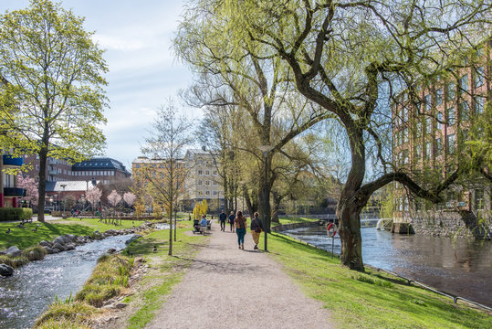 Unrecognizable people enjoy waterfront park Str&ouml;mparken along Motala river in Norrkoping during spring in Sweden.