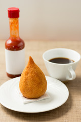 Coxinha is a deep fried food, traditional in Brazil. Snack, pepper sauce and coffee. Bar food. Selective focus.
