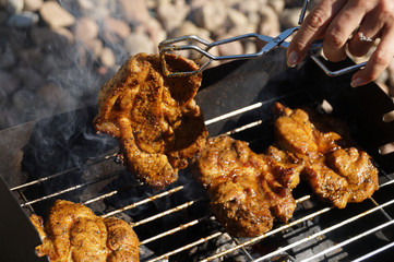 Grilled meat. A woman's hand turns the meat to the other side