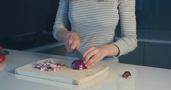 Young woman chopping onion in her kitchen