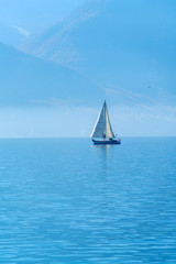 Fototapeta na wymiar A small sailing yacht on the Lake Geneva and the Alps, Switzerland