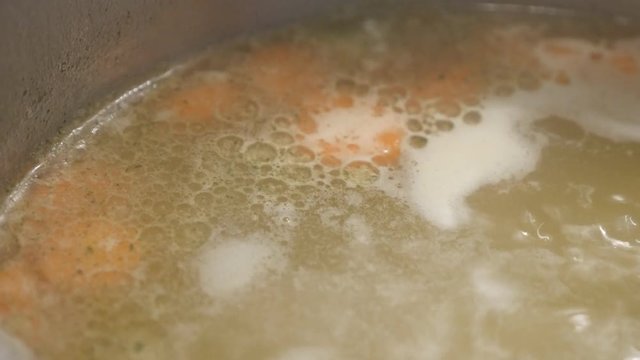 Close-up of hot water and vegetables footage - Greasy boiling soup in the pot 