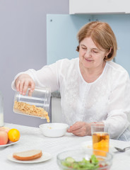 Senior woman at breakfast with corn flakes