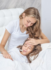 Obraz na płótnie Canvas Mother caressing a sick girl on the bed