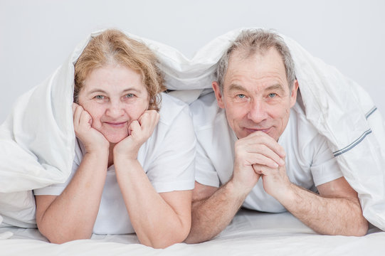 Smiling senior couple lying under the blanket together