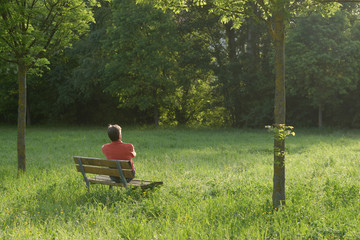 man relaxing on a bench who warms up in the early morning sun
