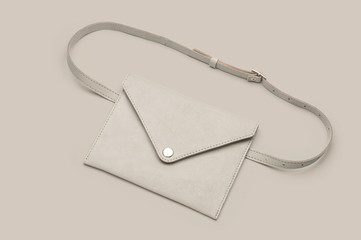 Women's white leather waist bag on beige background