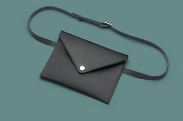 Women's black leather waist bag on green background