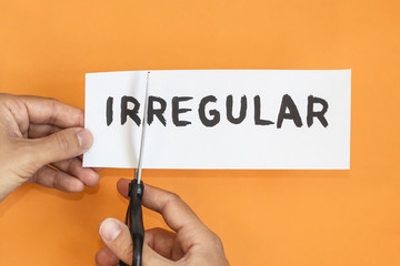 Closeup man cutting paper of irregular word. concept for self belief, positive attitude and...