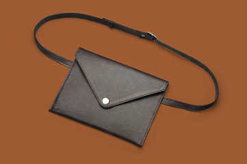 Women's brown leather waist bag on orange background