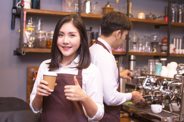 Asian women Barista smiling and looking to camera in coffee shop counter.  Barista female working at cafe. Working woman small business owner or sme concept.