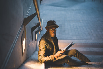 young handsome black man millennial using tablet outdoor night - technology, social network, remote working concept