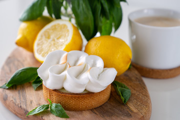 Lemon tartlets with basil on wooden desk and Cup of coffee on white table. Tasty treat on a light blue background.